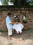 Hanoi - Friseur unter freiem Himmel (Foto 1 Dollar, siehe links neben dem Kopf des Meister-Figaros)